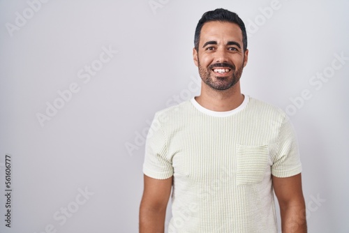 Hispanic man with beard standing over isolated background with a happy and cool smile on face. lucky person.