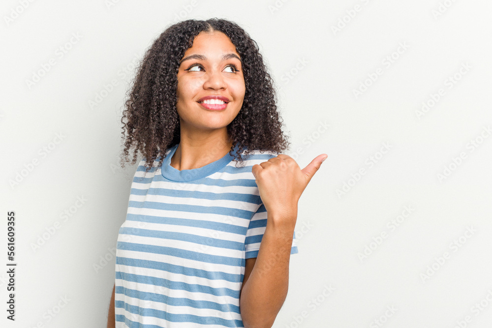 Young african american woman isolated on white background points with thumb finger away, laughing and carefree. Young african american woman isolated on white background points with thumb finger away, laughing and carefree.