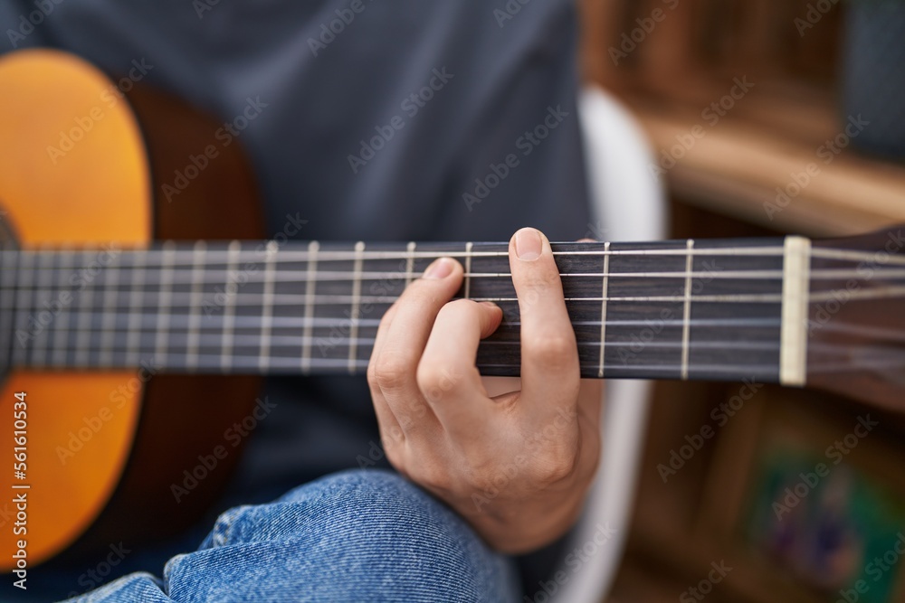 Young caucasian man playing classical guitar at home