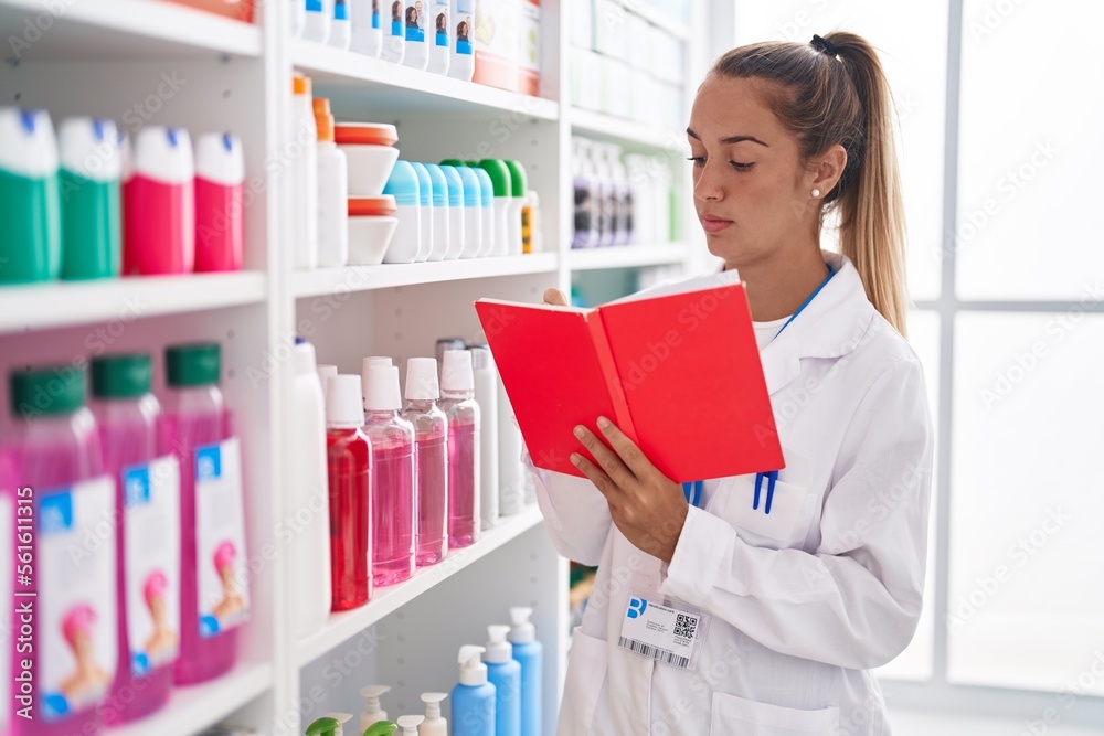 Young beautiful hispanic woman pharmacist reading book at pharmacy