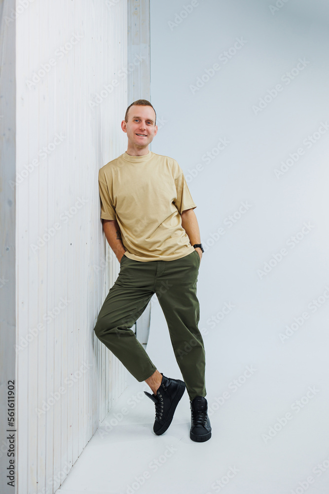Fototapeta premium A young handsome man in casual clothes poses on a white background in the studio