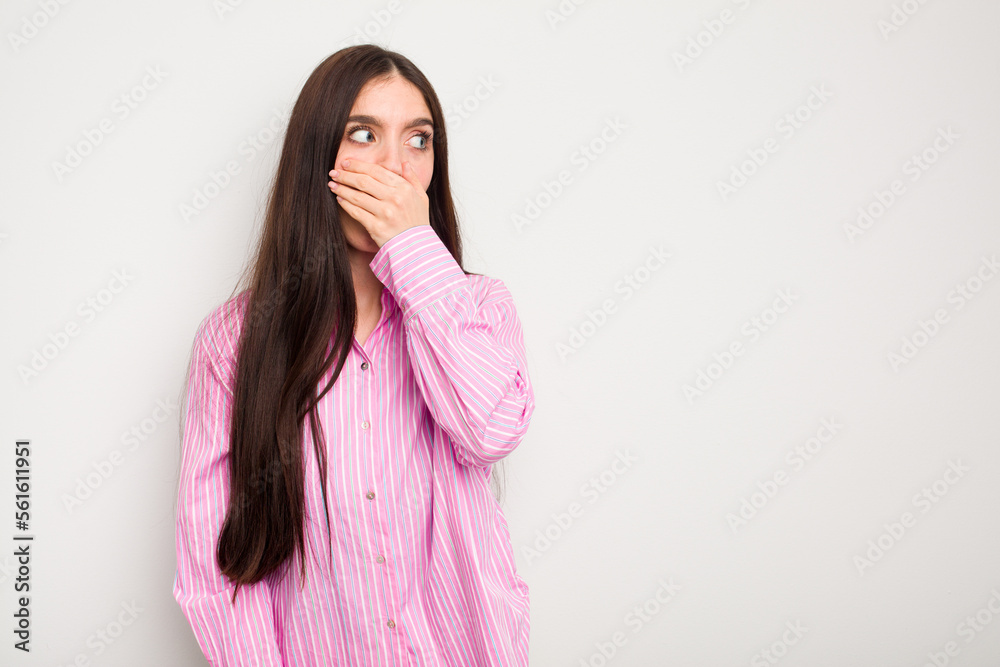 Fototapeta premium Young caucasian woman isolated on white background thoughtful looking to a copy space covering mouth with hand.