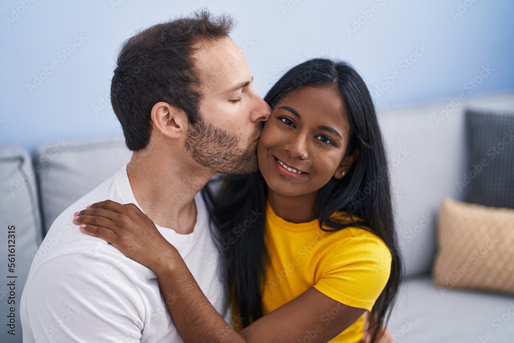 Man and woman interracial couple hugging each other and kissing at home Man and woman interracial couple hugging each other and kissing at home