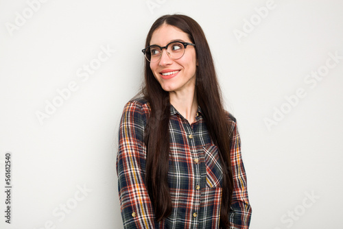 Young caucasian woman isolated on white background looks aside smiling, cheerful and pleasant.