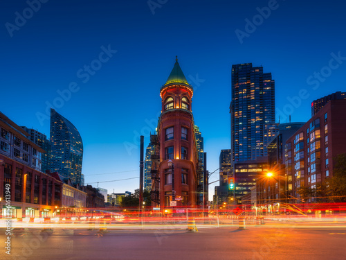 Canada, Toronto. The famous Gooderham building and the skyscrapers in the background. View of the city in the evening. Blurring traffic lights. Modern and ancient architecture. Night city. © biletskiyevgeniy.com