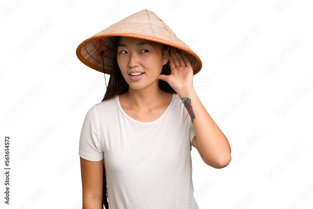 Φωτογραφία Young asian woman wearing a Vietnamese hat isolated trying to listening a gossip