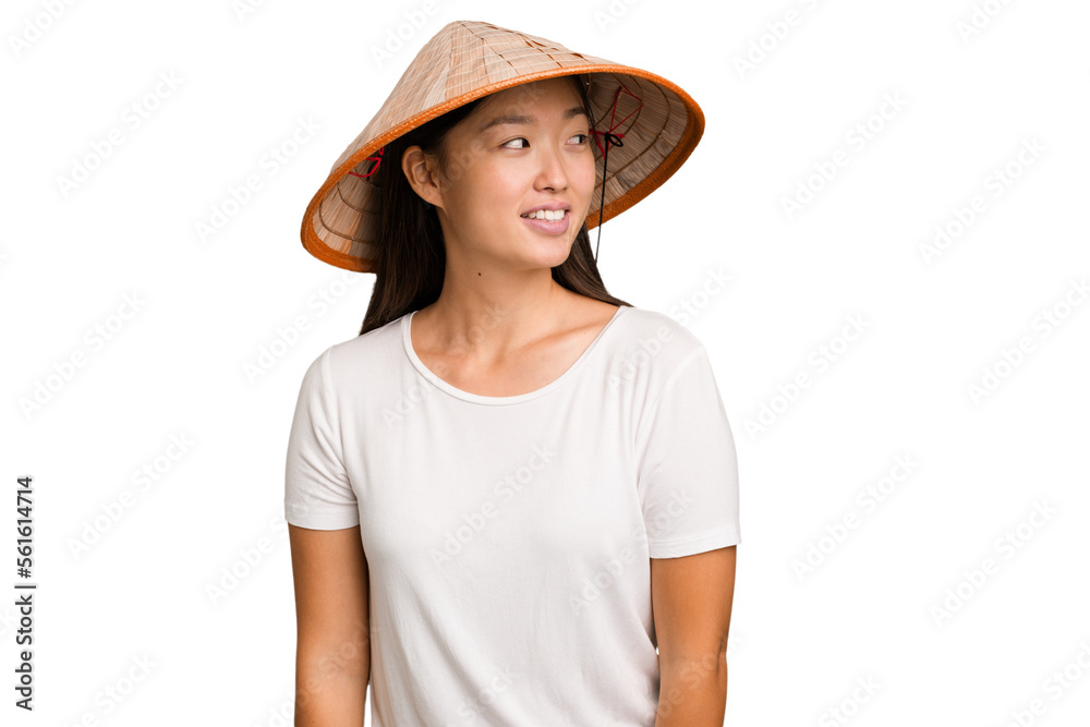 Young asian woman wearing a Vietnamese hat isolated looks aside smiling, cheerful and pleasant. Young asian woman wearing a Vietnamese hat isolated looks aside smiling, cheerful and pleasant.