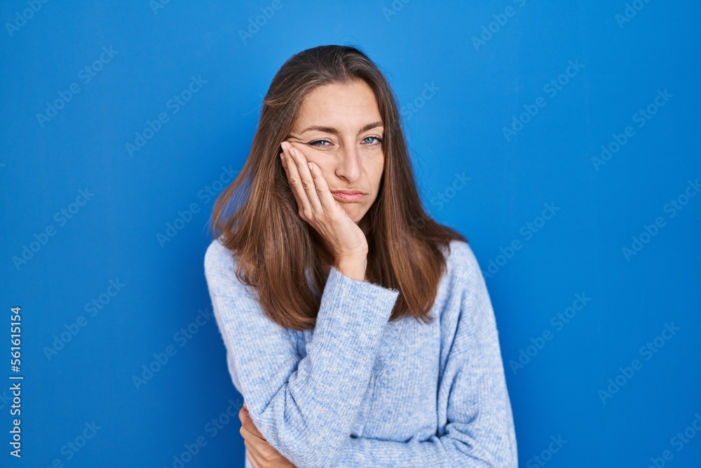 Young woman standing over blue background thinking looking tired and bored with depression problems with crossed arms. Young woman standing over blue background thinking looking tired and bored with depression problems with crossed arms.