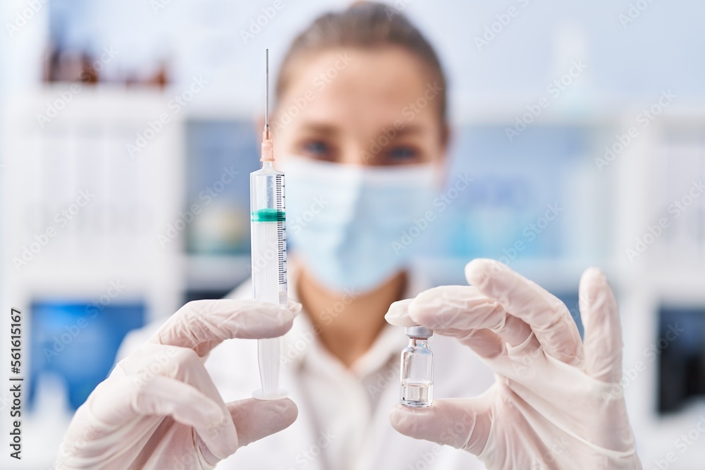 Fototapeta premium Young woman scientist holding covid vaccine at laboratory