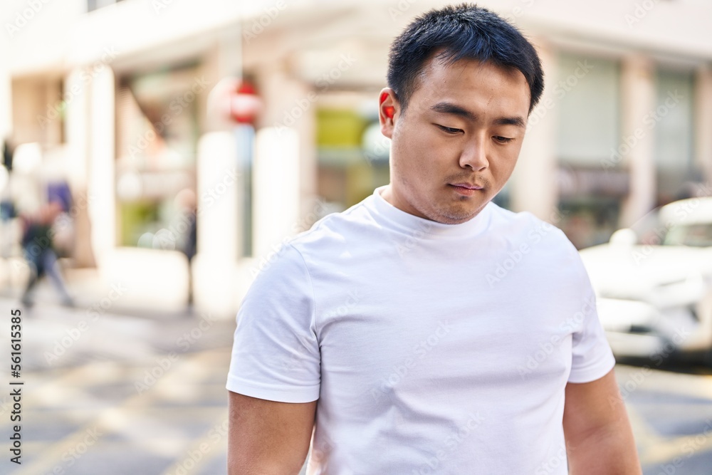 Young chinese man standing with relaxed expression at street Young chinese man standing with relaxed expression at street