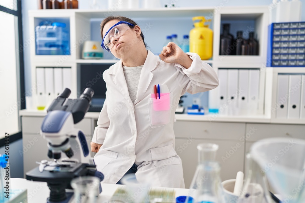 Hispanic girl with down syndrome working at scientist laboratory stretching back, tired and relaxed, sleepy and yawning for early morning Hispanic girl with down syndrome working at scientist laboratory stretching back, tired and relaxed, sleepy and yawning for early morning