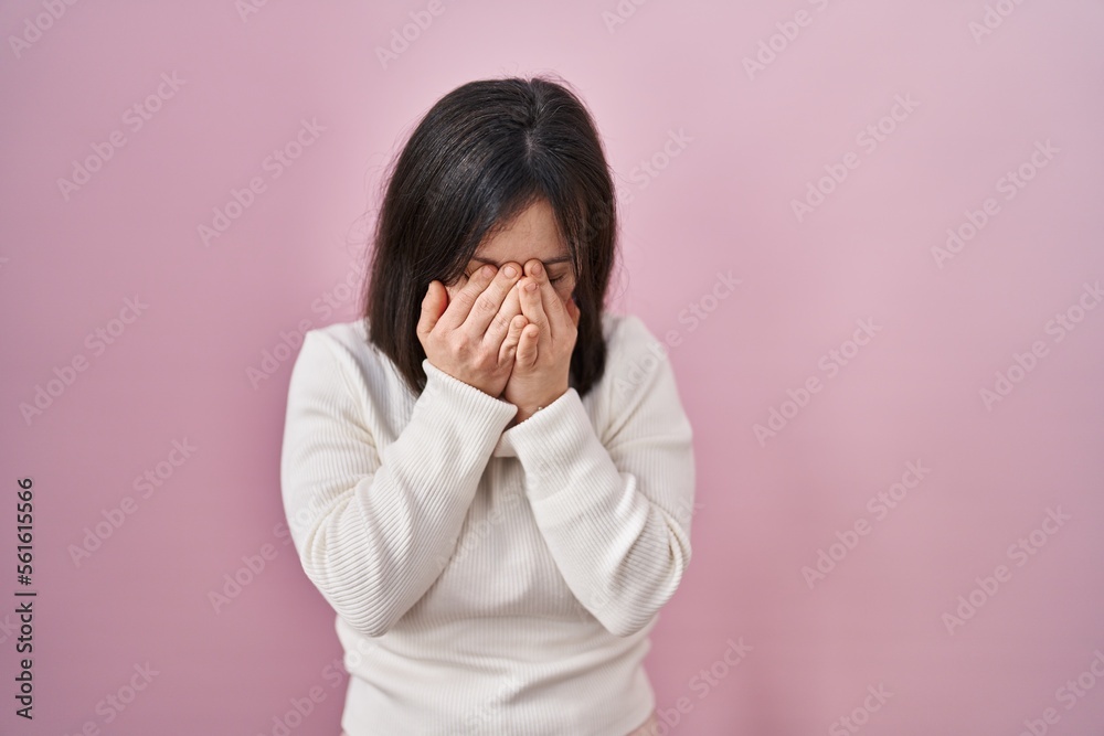 Woman with down syndrome standing over pink background rubbing eyes for fatigue and headache, sleepy and tired expression. vision problem Woman with down syndrome standing over pink background rubbing eyes for fatigue and headache, sleepy and tired expression. vision problem