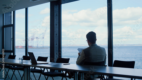 Unknown director reading papers at ocean view. Businessman studying contract