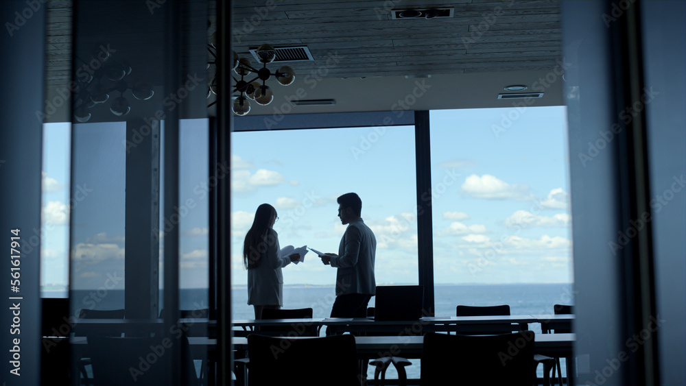 Partners silhouettes discussing contract at panorama window. Team talking Partners silhouettes discussing contract at panorama window. Team talking