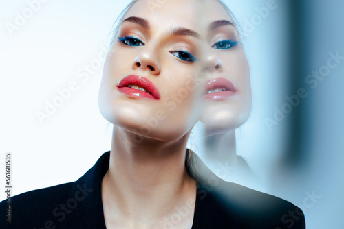 Portrait of businesslike white woman with reflection in mirror.  Bright makeup and glowing skin