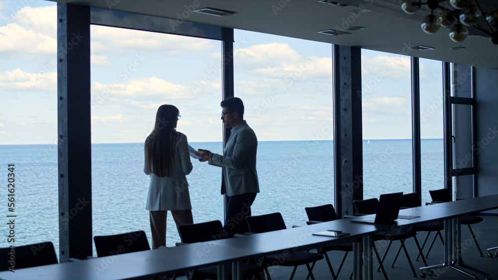 Manager discussing worker planning at panorama window. Two business people talk Manager discussing worker planning at panorama window. Two business people talk