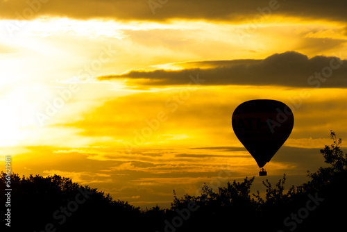hot air ballon at sundown against a yellow and shining gorgeous couldy sky photo