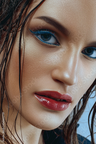 Portrait of caucasian woman with blue arrows and shiny tanned skin in close-up. Wet hair, strong look photo