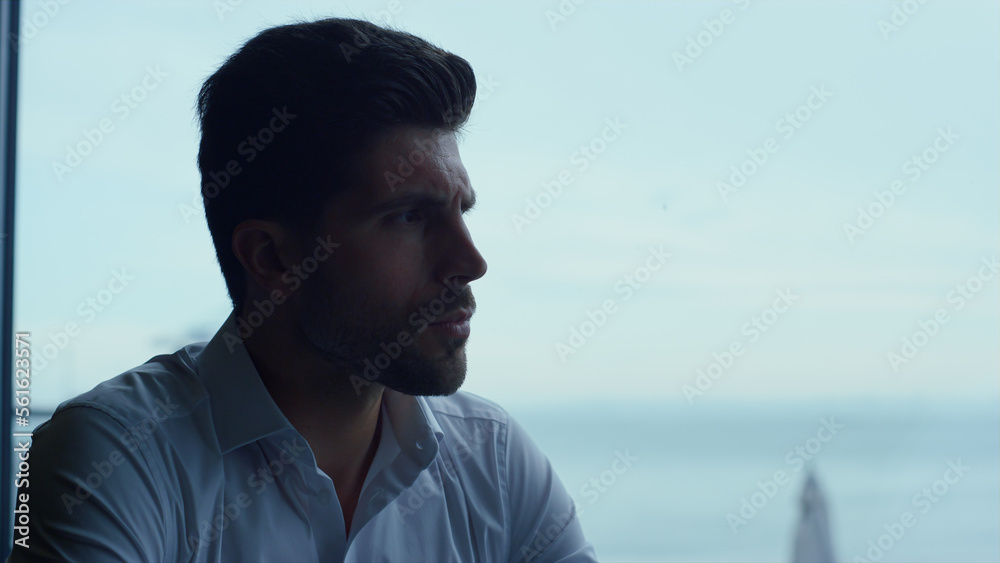Handsome man spending leisure time in dark panoramic restaurant alone profile