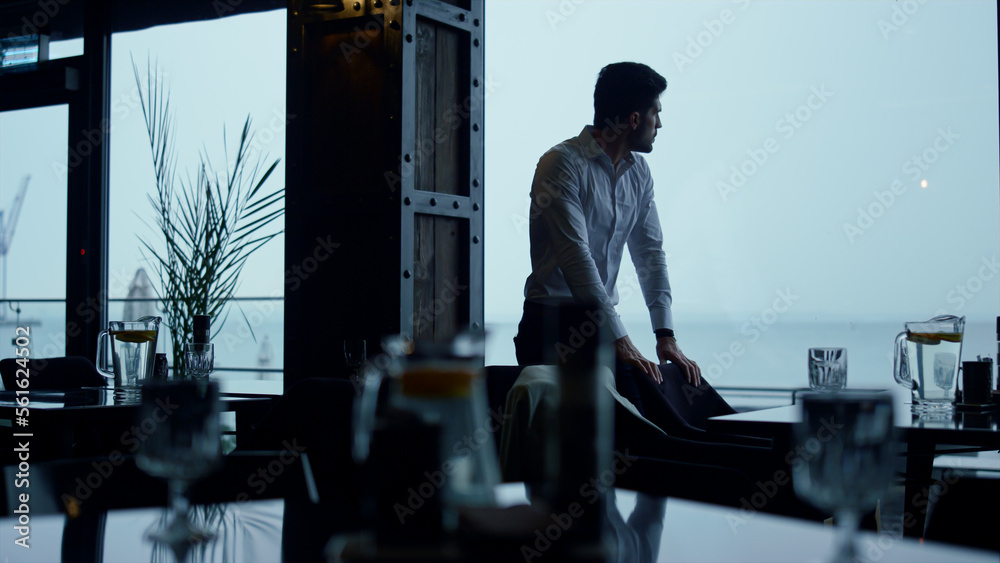 Handsome businessman enjoying beautiful ocean view in panoramic restaurant hall Handsome businessman enjoying beautiful ocean view in panoramic restaurant hall