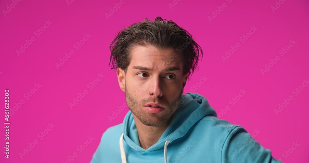 project video of sexy Arabic man in blue hoodie adjusting long curly hair, moving head and playing on pink background project video of sexy Arabic man in blue hoodie adjusting long curly hair, moving head and playing on pink background