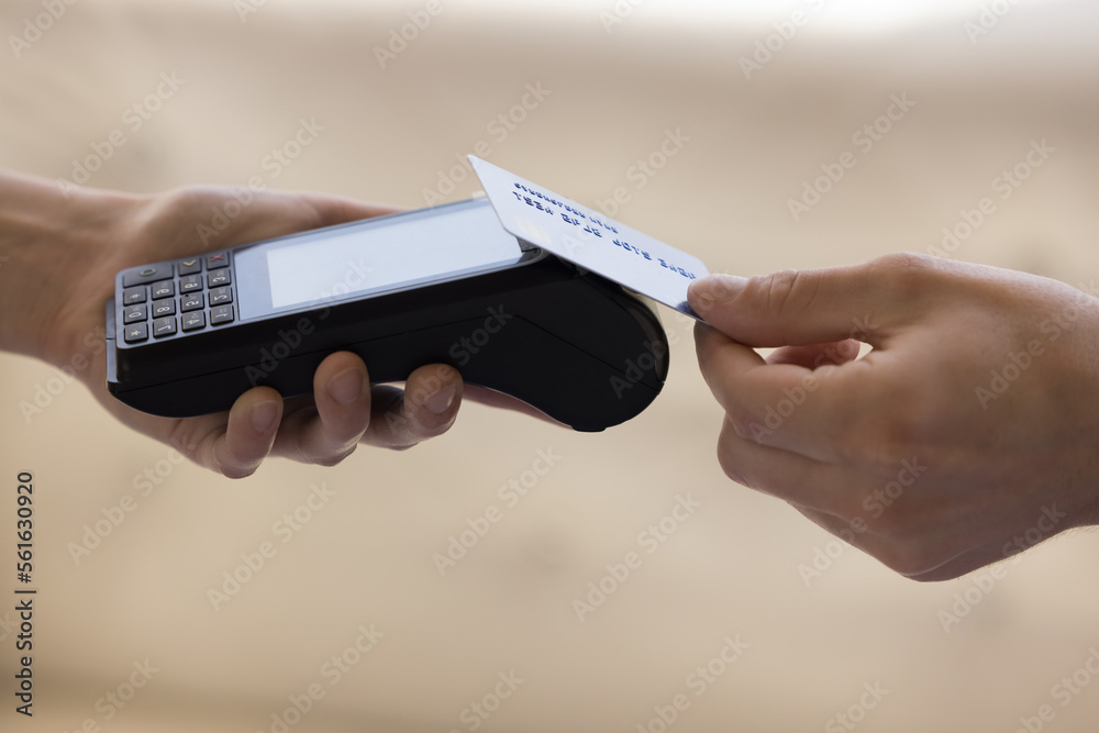 Hands of seller woman and buyer man using payment terminal device and credit card side view close up. Customer, bank client, cardholder paying for purchase, service, shipping - obrazy, fototapety, plakaty 