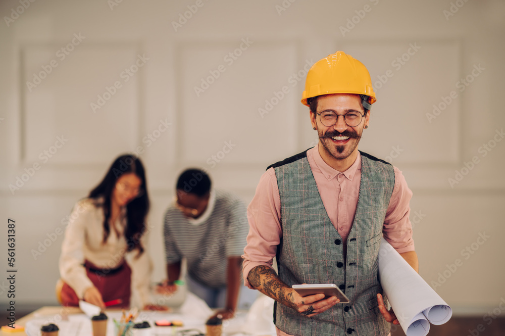 Male architect using blueprint and tablet in an office during a meeting Male architect using blueprint and tablet in an office during a meeting