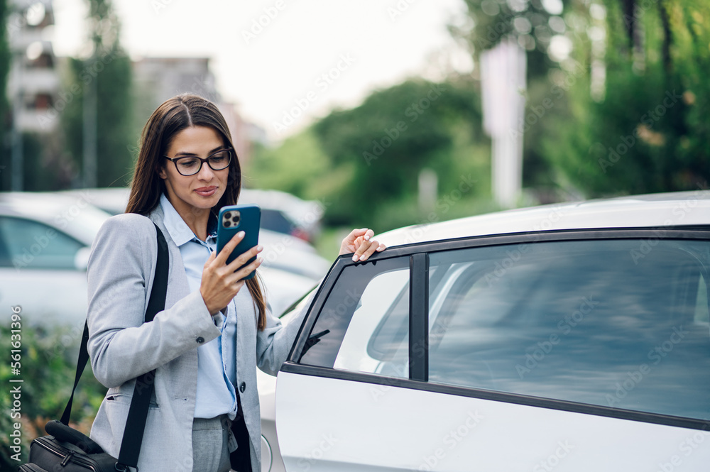 Business woman getting into the car and using smartphone Business woman getting into the car and using smartphone