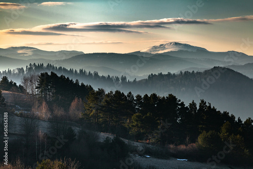 Mglisty poranny krajobraz ośnieżonych połonin z widokiem gór na horyzoncie oraz górskich zamglonych lasów, Bieszczady, Polska