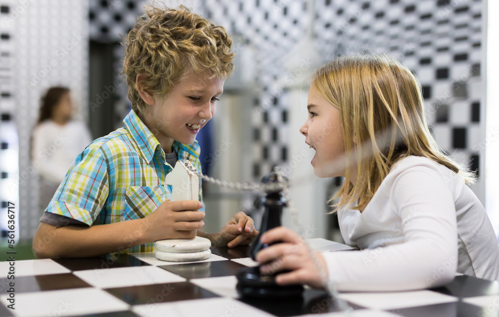 Curious boy and girl discuss the game in the chess quest room