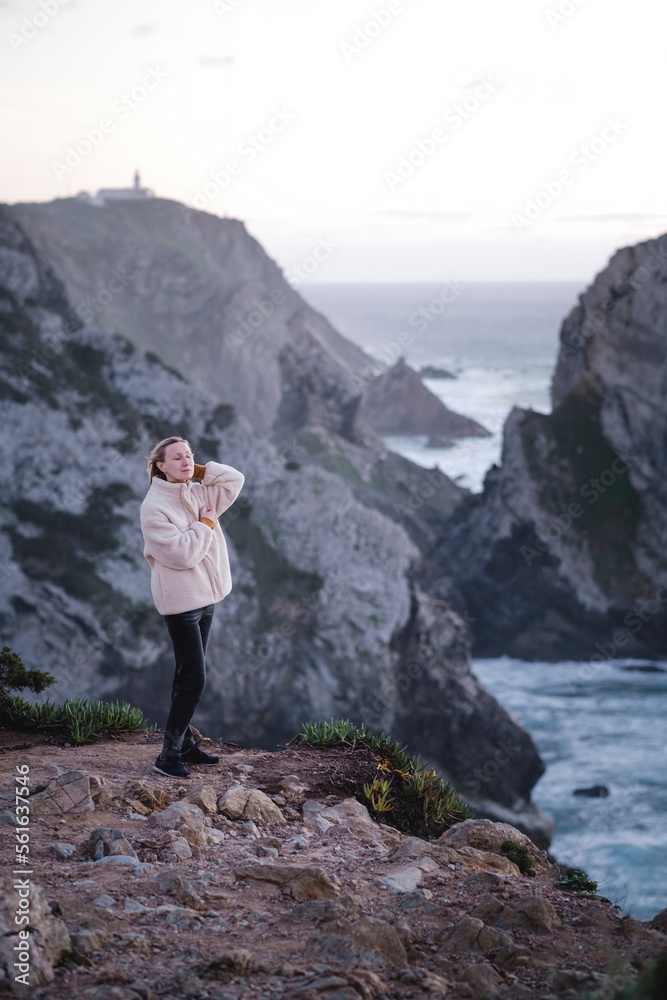 A woman stands on the Atlantic cliffs near Cape Roca, Sintra, Portugal.