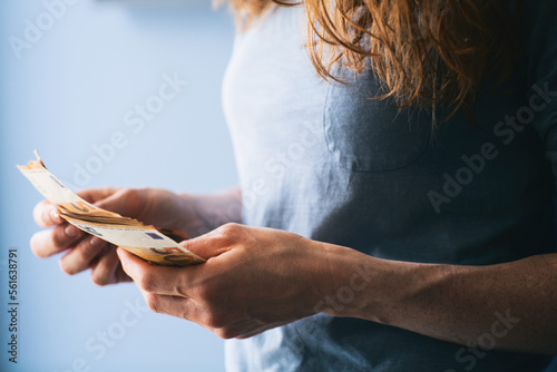 Closeup shot of a woman counting Euro cash against a blue background