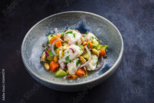 Traditional Peruvian gourmet ceviche sea bass filet piece with sweet potatoes and cancha marinated and served in lime sauce as close-up in a Nordic design bowl