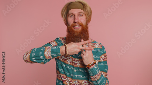 Cheerful hippie redhead man in pattern shirt showing hashtag symbol with hands, likes tagged message popular viral content sign to follow internet online trends. Hipster bearded guy on pink background