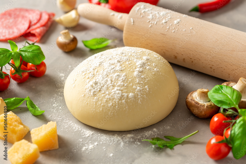 Fresh dough with set ingredients for cooking italian pizza on a light stone table Fresh dough with set ingredients for cooking italian pizza on a light stone table