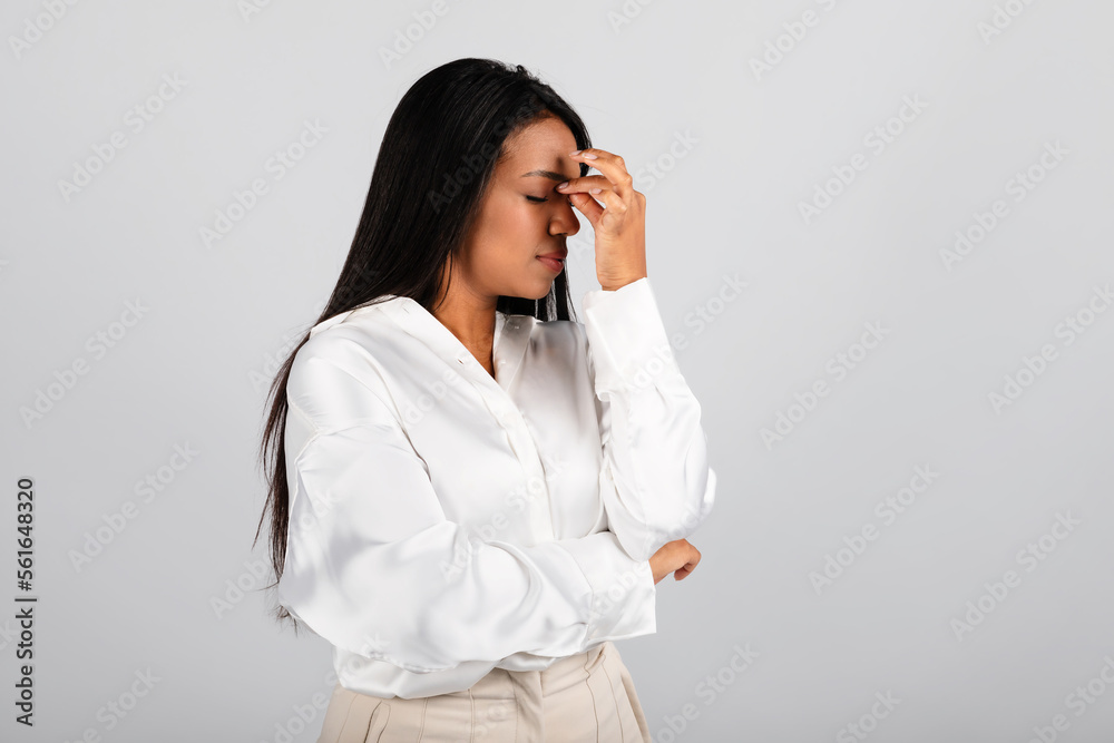 Unhappy upset millennial black woman in white blouse holding head with hand, suffering from pain Unhappy upset millennial black woman in white blouse holding head with hand, suffering from pain