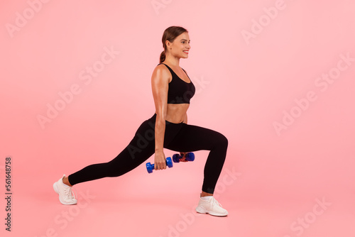 Sporty Young Woman Holding Dumbbells And Making Deep Lunges Exercise In Studio © Prostock-studio