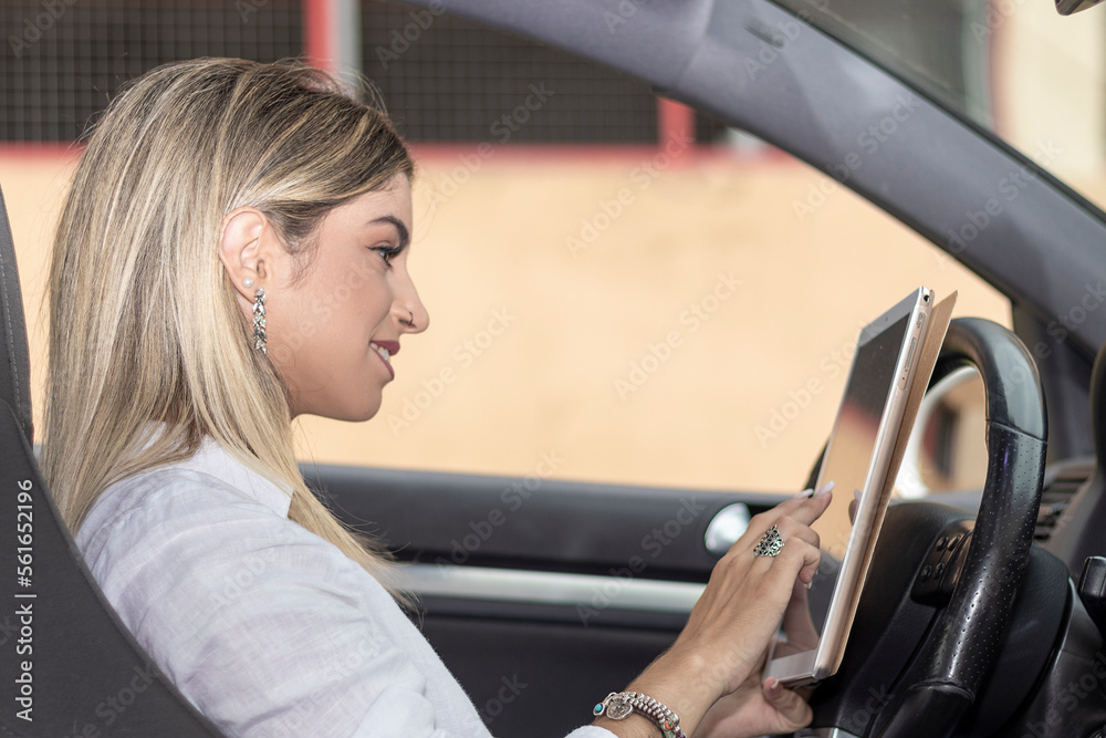 Close up portrait of a young business woman using digital tablet in the seat of the car
