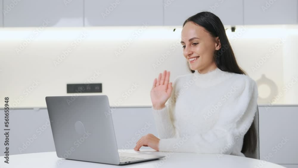 Young female team leader greets participants of webinar gladly sitting in light room. Smiling woman happy to share knowledge. Online communication Young female team leader greets participants of webinar gladly sitting in light room. Smiling woman happy to share knowledge. Online communication