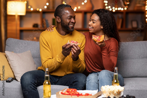 Fototapeta Portrait of happy african american lovers eating pizza at home