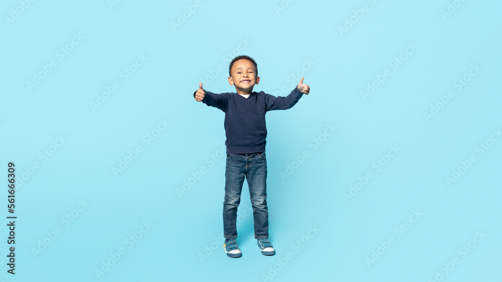 Sincere approval. Full length shot portrait of carefree little african american boy smiling and showing thumbs up Sincere approval. Full length shot portrait of carefree little african american boy smiling and showing thumbs up