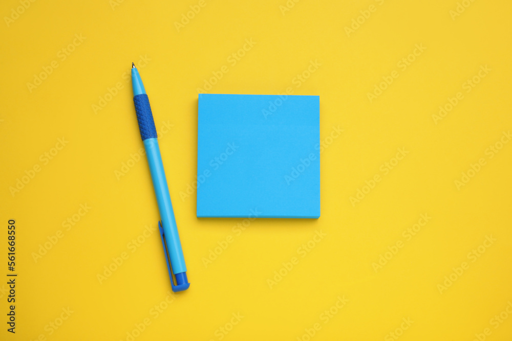 Paper notes and pen on yellow background, flat lay Paper notes and pen on yellow background, flat lay