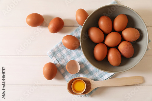 Cracked and whole chicken eggs on white wooden table, flat lay