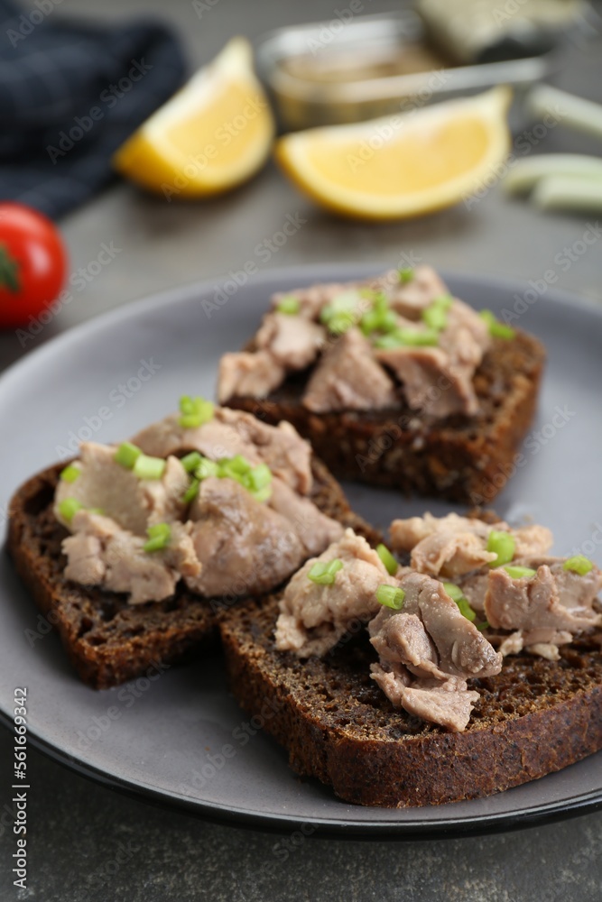 Tasty sandwiches with cod liver and green onion on light grey table