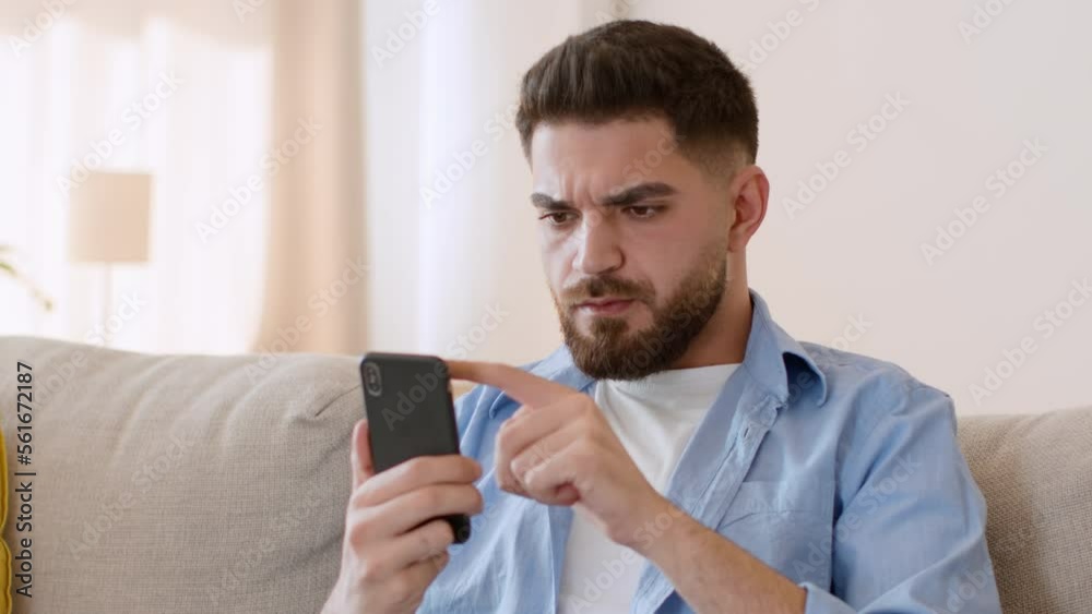 Online content. Young arab guy reading news in internet on smartphone, resting at home, tracking shot, empty space Online content. Young arab guy reading news in internet on smartphone, resting at home, tracking shot, empty space