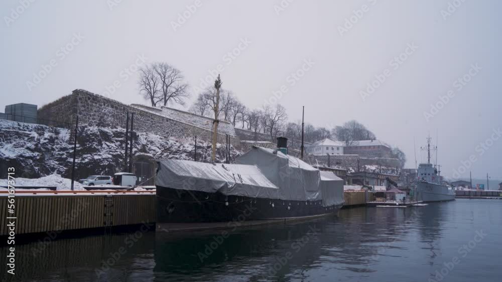 Covered Boat And Navel Vessel Moored At Harbour Beside Akershus Castle During Winter. Static Shot Covered Boat And Navel Vessel Moored At Harbour Beside Akershus Castle During Winter. Static Shot