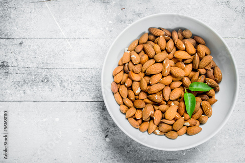 Almonds in a bowl with green leaves .