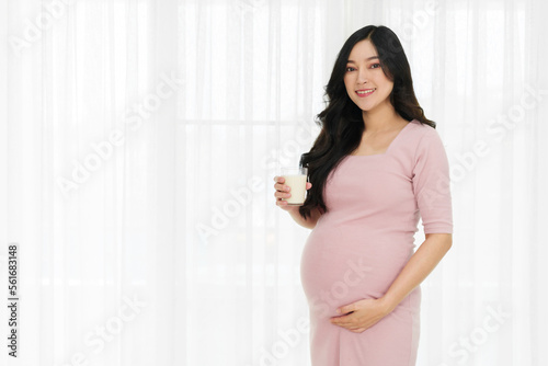 pregnant woman drinking a milk at the window in bedroom