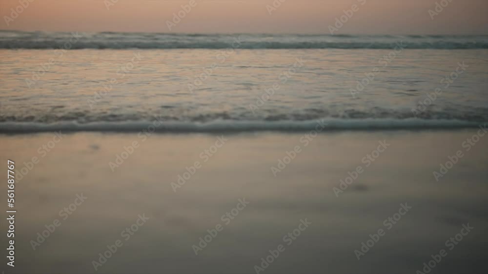 Small foaming waves gently crashing against the sand on the shore at dawn Small foaming waves gently crashing against the sand on the shore at dawn