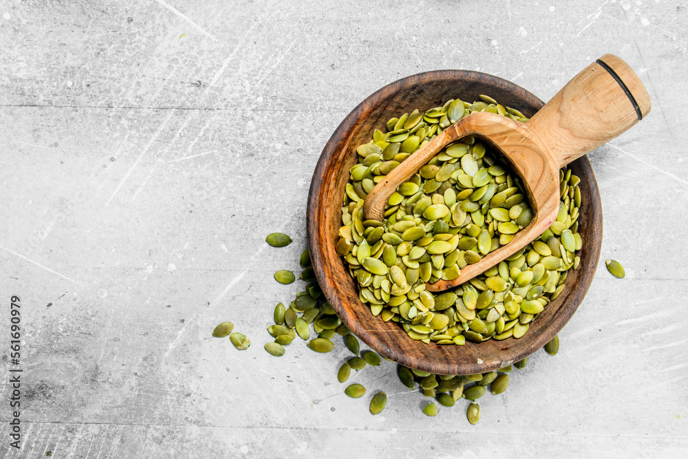Pumpkin seeds in bowl with wooden scoop. Pumpkin seeds in bowl with wooden scoop.